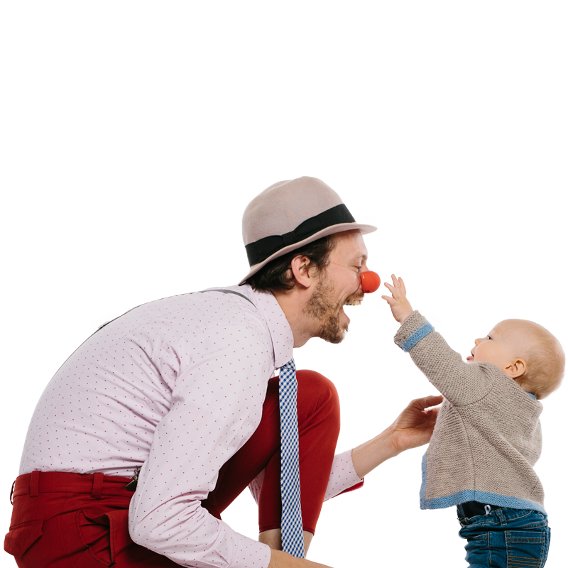 Clown und Baby in Interaktion, Baby greift dem Clown auf die Nase